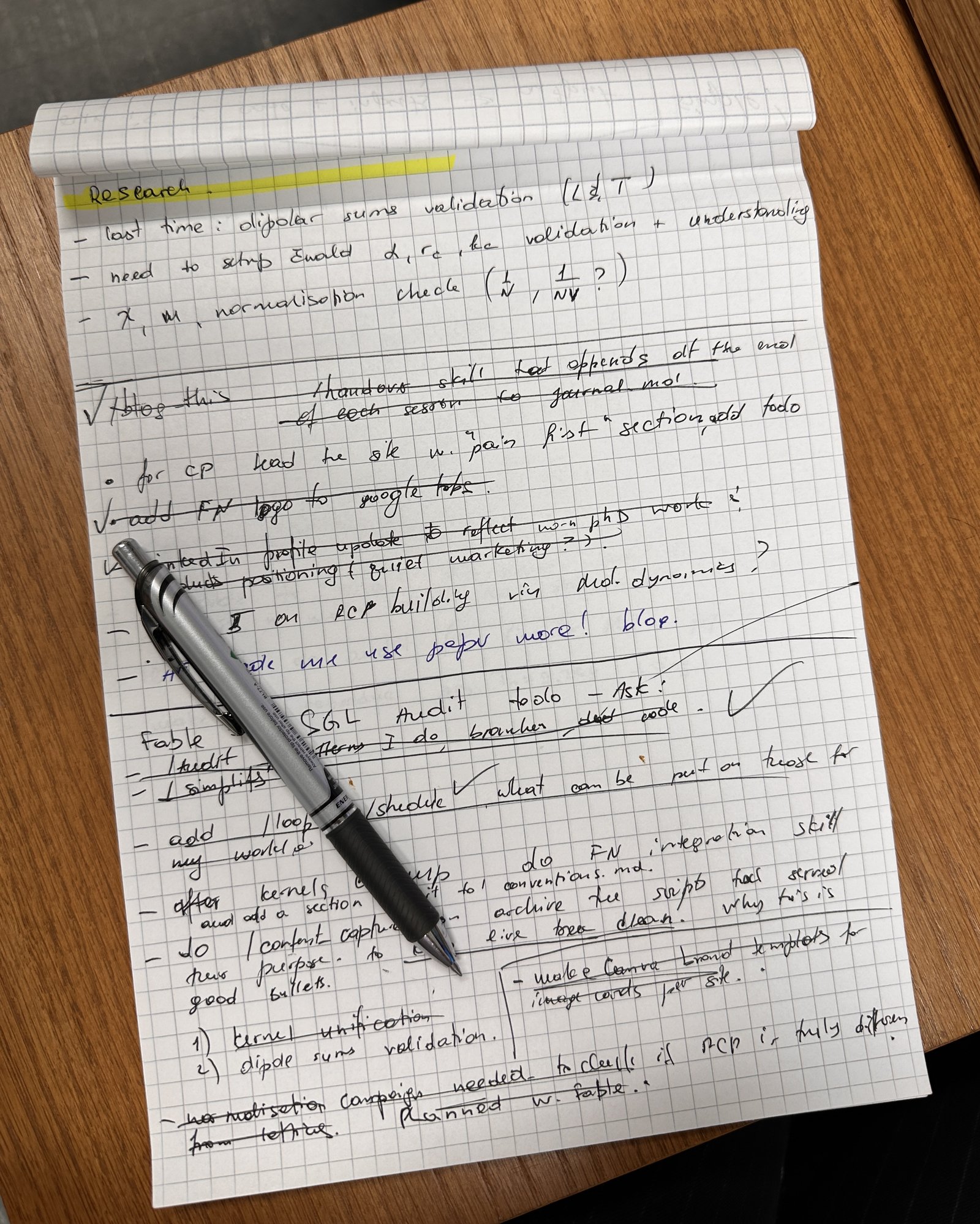 A grid notepad page filled with short handwritten notes, most struck through, with a pen lying on top